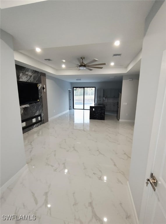 unfurnished living room featuring recessed lighting, visible vents, baseboards, marble finish floor, and a tray ceiling