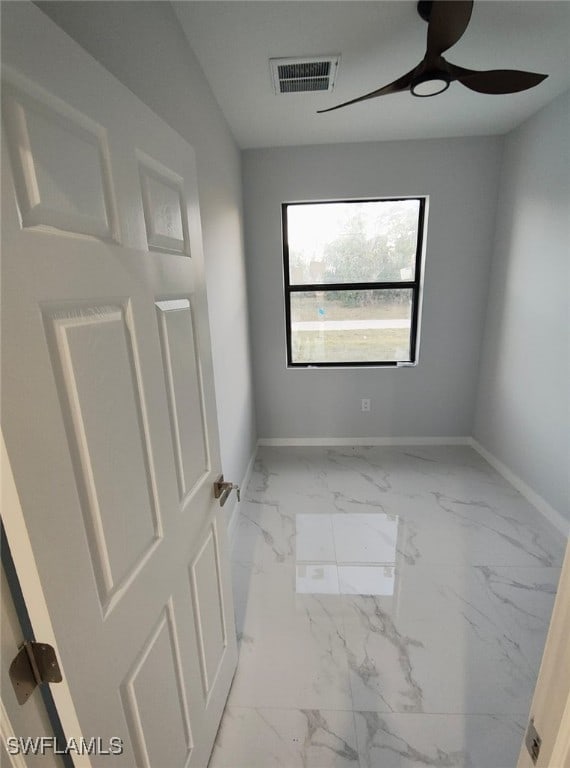 empty room featuring marble finish floor, baseboards, visible vents, and a ceiling fan