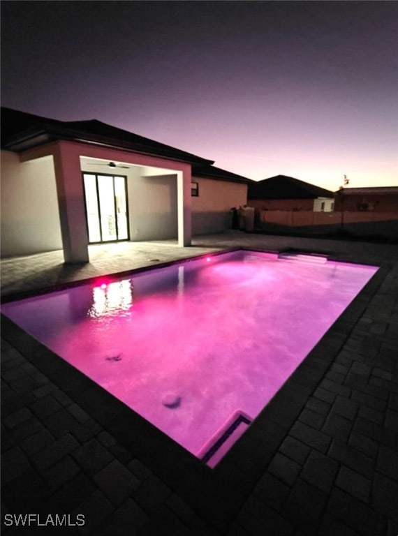 pool at dusk with a patio area and an outdoor pool