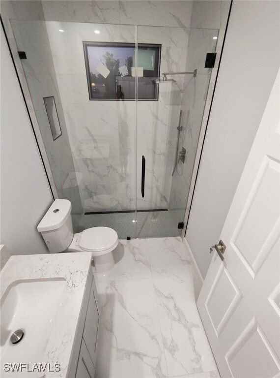 full bath with marble finish floor, toilet, vanity, and a marble finish shower