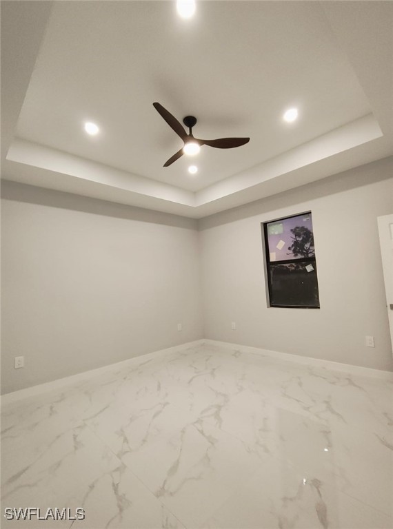 spare room featuring marble finish floor, recessed lighting, a raised ceiling, ceiling fan, and baseboards