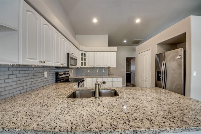 kitchen with light stone counters, appliances with stainless steel finishes, a sink, and visible vents