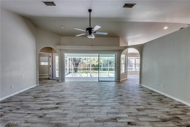 unfurnished living room featuring arched walkways, baseboards, visible vents, and a ceiling fan