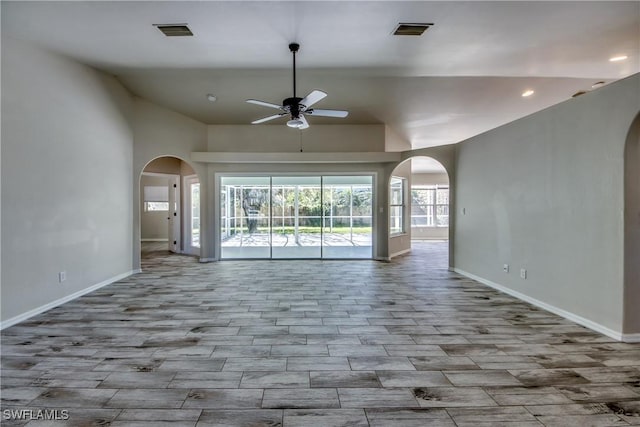 unfurnished living room with arched walkways, visible vents, and baseboards