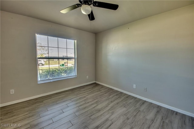 empty room with ceiling fan, baseboards, and wood finished floors