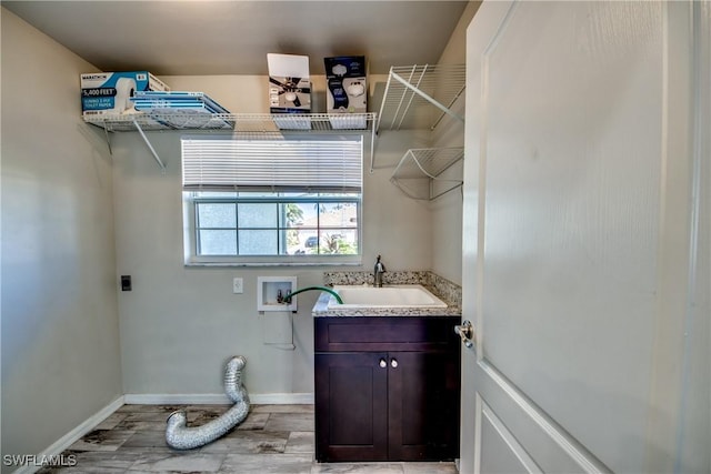 washroom featuring cabinet space, baseboards, electric dryer hookup, washer hookup, and a sink