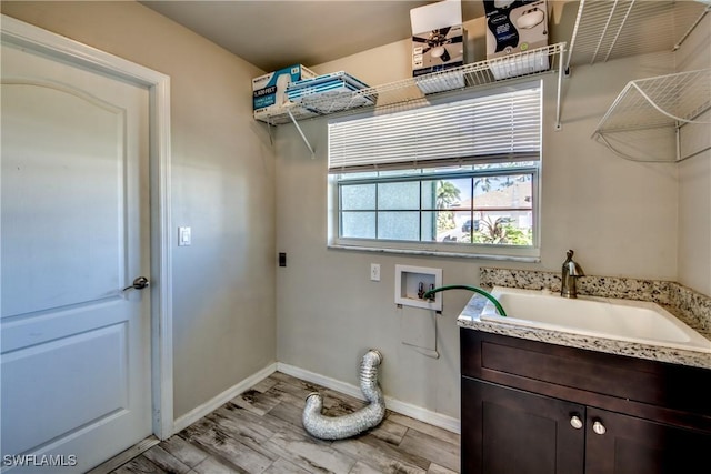 washroom featuring washer hookup, a sink, baseboards, light wood finished floors, and electric dryer hookup