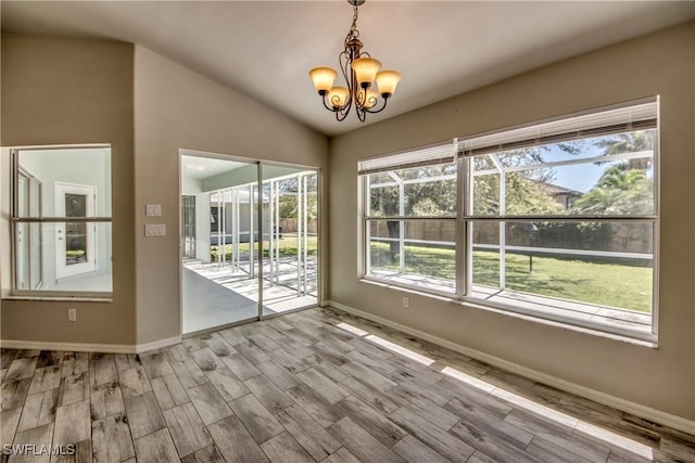 empty room with wood finished floors, vaulted ceiling, baseboards, and an inviting chandelier