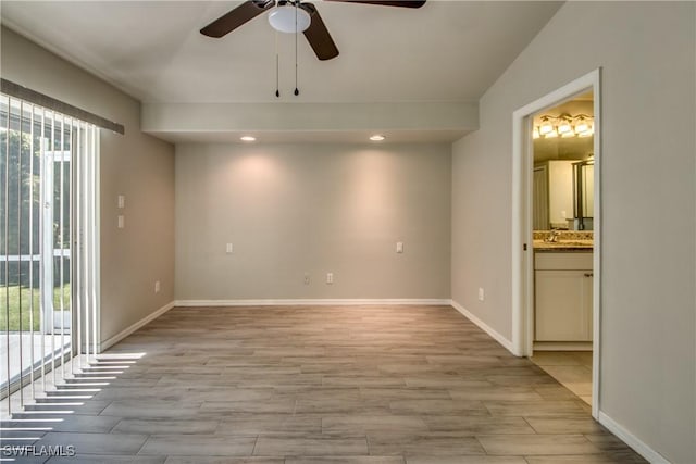 empty room featuring light wood finished floors, recessed lighting, a ceiling fan, a sink, and baseboards