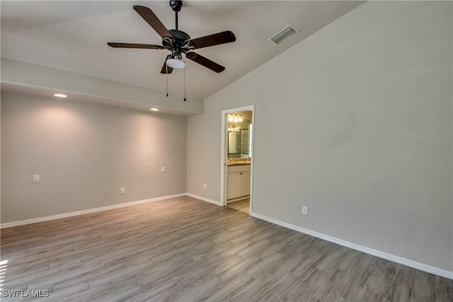 empty room with lofted ceiling, visible vents, light wood-style flooring, ceiling fan, and baseboards