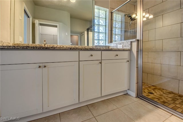 bathroom with tile patterned flooring, a shower stall, and vanity