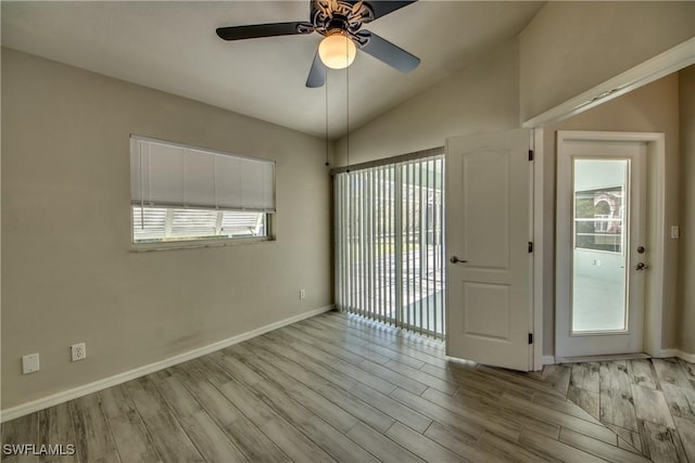 unfurnished room with lofted ceiling, plenty of natural light, baseboards, and wood finished floors