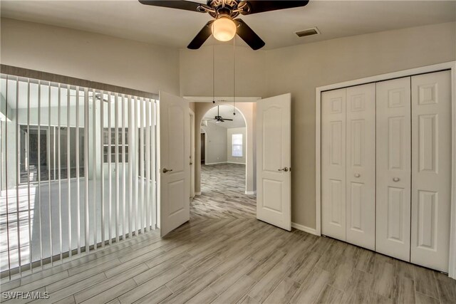 unfurnished dining area featuring arched walkways, wood finished floors, visible vents, baseboards, and a ceiling fan