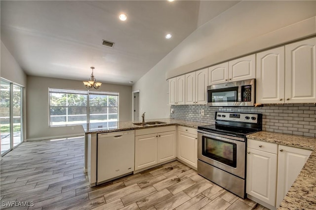 kitchen with stainless steel appliances, lofted ceiling, decorative backsplash, a sink, and a peninsula