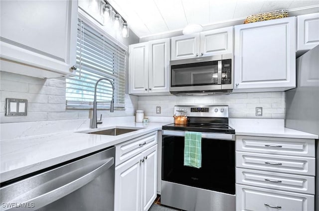 kitchen with stainless steel appliances, white cabinetry, a sink, and tasteful backsplash