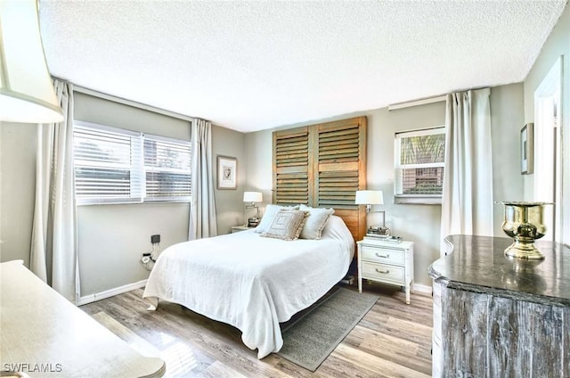 bedroom featuring a textured ceiling, baseboards, and wood finished floors