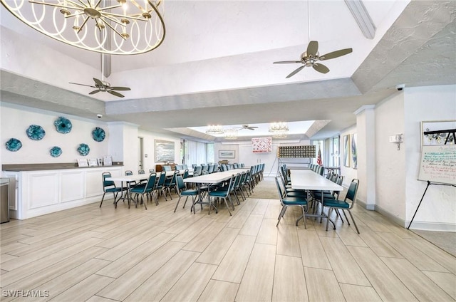 dining room featuring wood tiled floor, baseboards, a raised ceiling, and ceiling fan with notable chandelier