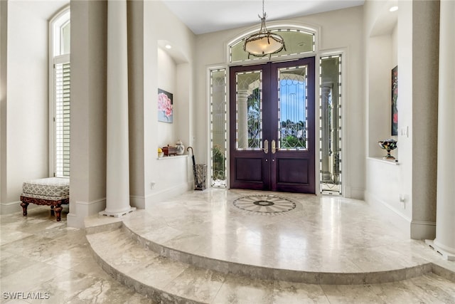 foyer with marble finish floor, decorative columns, and baseboards