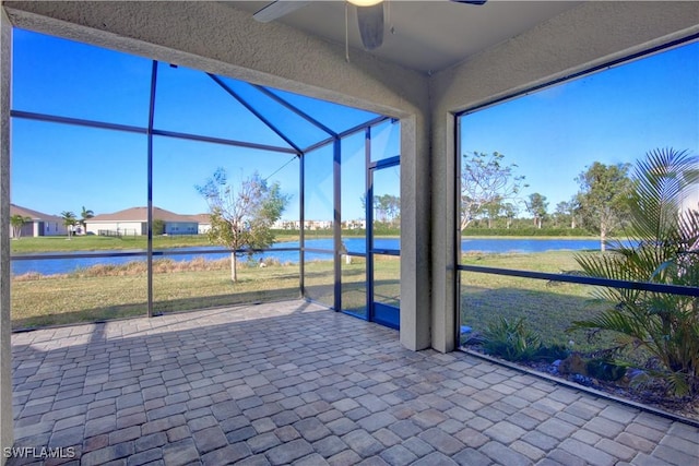 unfurnished sunroom featuring ceiling fan and a water view