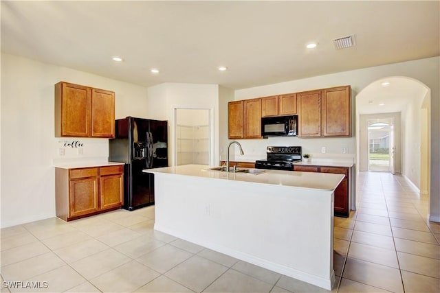 kitchen with black appliances, a sink, visible vents, and brown cabinets