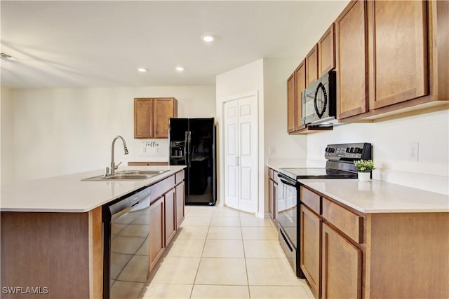 kitchen featuring light tile patterned floors, brown cabinets, light countertops, black appliances, and a sink