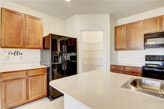 kitchen with a sink, black appliances, light tile patterned floors, and light countertops