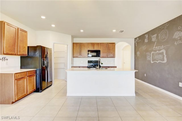 kitchen with black appliances, arched walkways, light countertops, and a sink