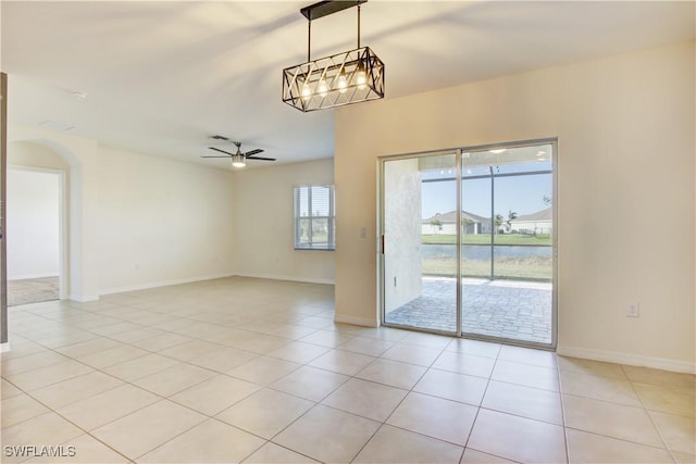 spare room featuring light tile patterned floors, ceiling fan with notable chandelier, and baseboards