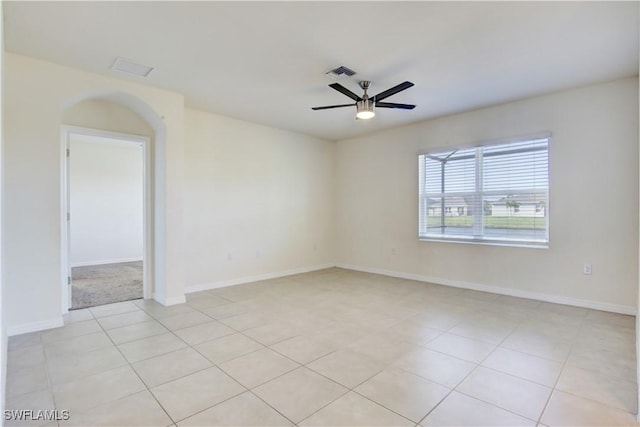 empty room featuring baseboards, visible vents, a ceiling fan, and light tile patterned flooring