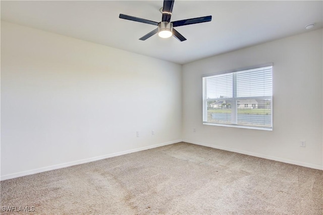 carpeted spare room featuring ceiling fan and baseboards