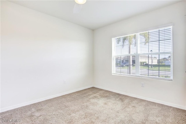 carpeted spare room with a ceiling fan, plenty of natural light, and baseboards