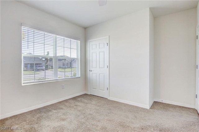 carpeted empty room featuring baseboards