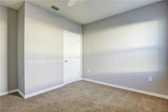 carpeted spare room with visible vents, ceiling fan, and baseboards