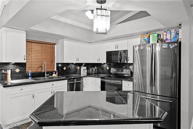 kitchen featuring a raised ceiling, stainless steel appliances, dark countertops, and a sink