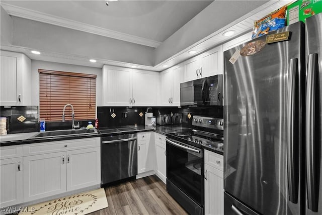 kitchen featuring ornamental molding, dark countertops, a sink, and black appliances