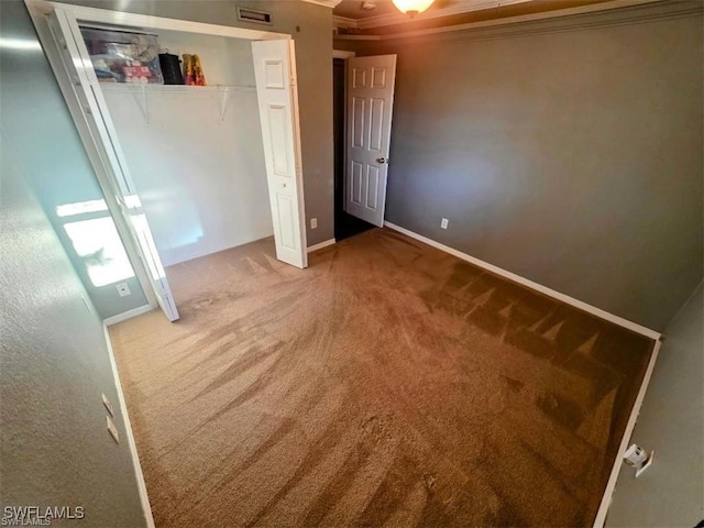 unfurnished bedroom with baseboards, visible vents, carpet, crown molding, and a closet