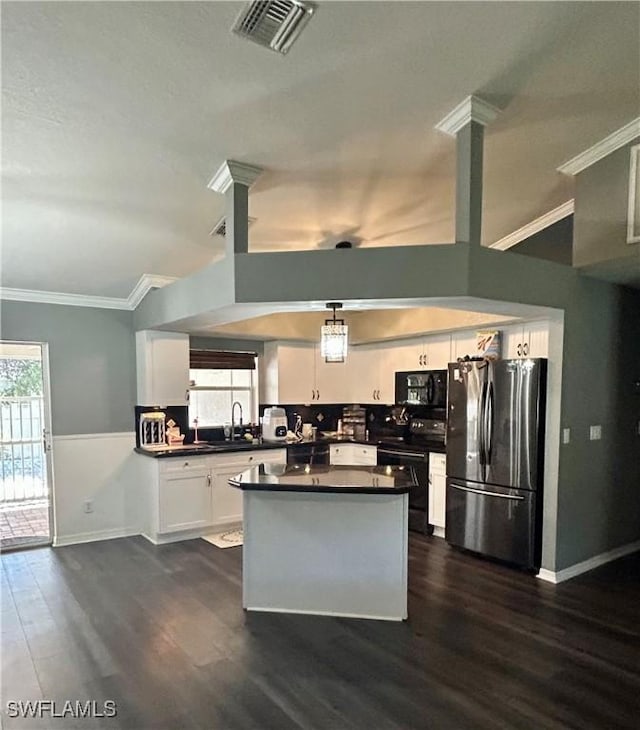 kitchen featuring black microwave, range with electric cooktop, visible vents, freestanding refrigerator, and dark countertops