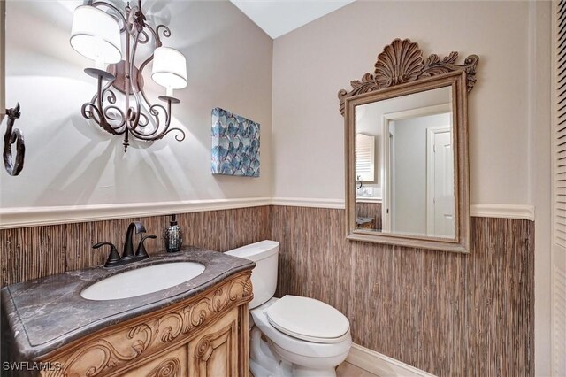 bathroom featuring a wainscoted wall, toilet, and vanity