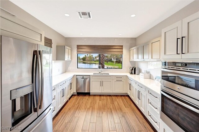 kitchen with stainless steel appliances, a sink, light countertops, decorative backsplash, and recessed lighting