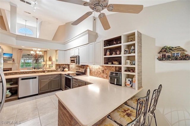 kitchen featuring stainless steel appliances, a peninsula, tasteful backsplash, open shelves, and lofted ceiling