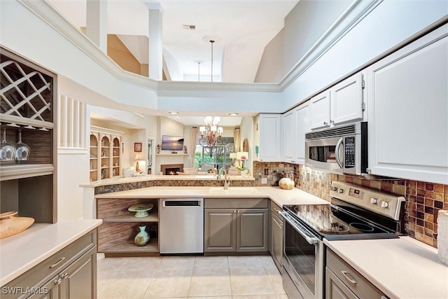 kitchen with stainless steel appliances, a sink, open shelves, gray cabinetry, and light tile patterned flooring