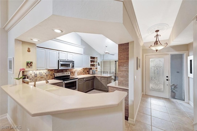 kitchen featuring a peninsula, a sink, light countertops, appliances with stainless steel finishes, and decorative backsplash