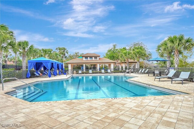 community pool with fence, a patio area, and a gazebo