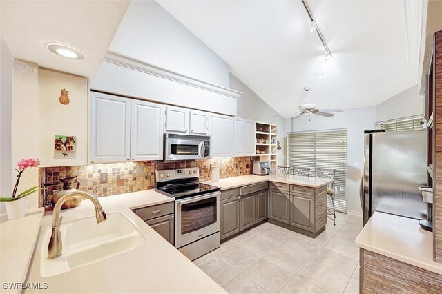 kitchen featuring gray cabinetry, stainless steel appliances, a peninsula, a sink, and vaulted ceiling