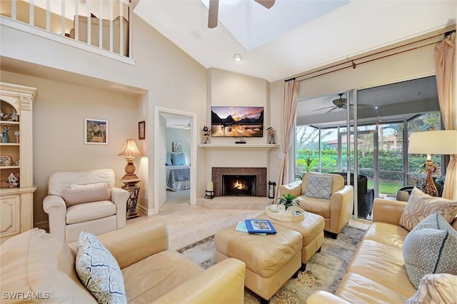 living area featuring a skylight, ceiling fan, a fireplace, and high vaulted ceiling