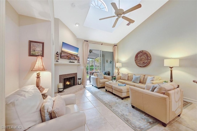 living room with a warm lit fireplace, high vaulted ceiling, a ceiling fan, and light tile patterned flooring