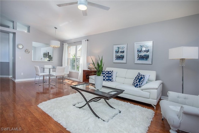 living area with baseboards, lofted ceiling, wood finished floors, and a ceiling fan