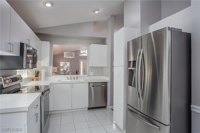 kitchen with lofted ceiling, a sink, stainless steel appliances, light countertops, and white cabinetry