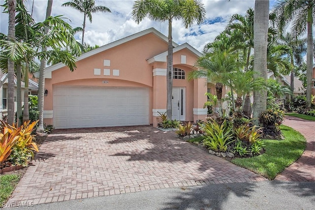 mediterranean / spanish-style home featuring stucco siding, decorative driveway, and a garage