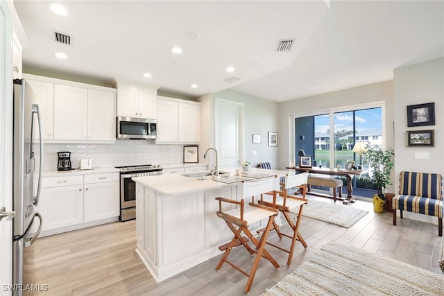 kitchen featuring a breakfast bar, visible vents, stainless steel appliances, and a sink